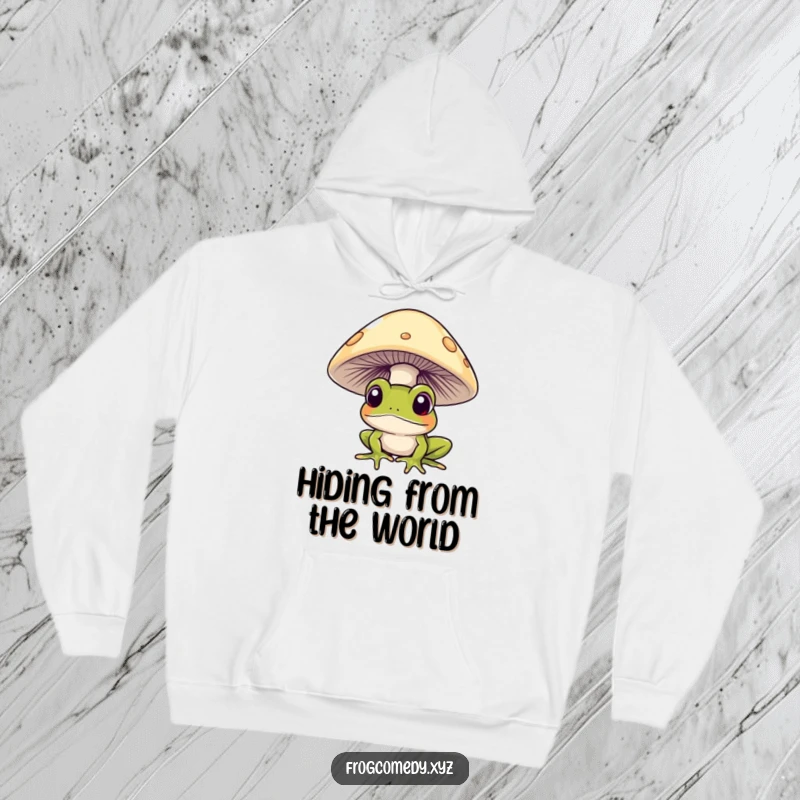 Funny frog curiously peeking from under a mushroom, on a cozy hoodie, for comfortable and humorous wear.