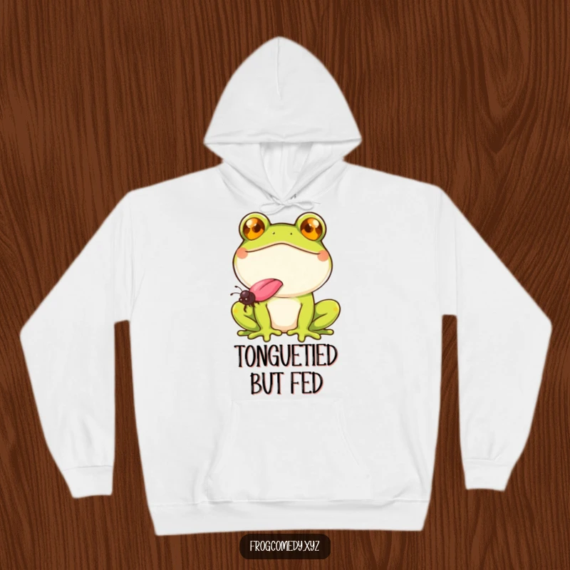Funny frog with a wide smile, catching a fly with its tongue, on a cozy hoodie, for comfortable and humorous wear.